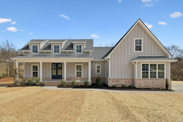 view of front of property featuring roof with shingles, covered porch, french doors, board and batten siding, and brick siding