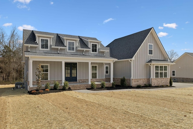 view of front of property featuring roof with shingles, a porch, french doors, board and batten siding, and brick siding