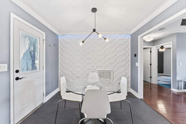 dining room featuring wood finished floors, a textured ceiling, baseboards, and ornamental molding