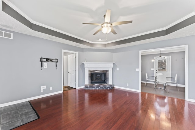 unfurnished living room with visible vents, a fireplace, baseboards, and wood finished floors