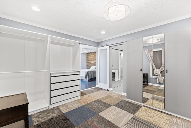 interior space with a barn door, ornamental molding, baseboards, and a textured ceiling