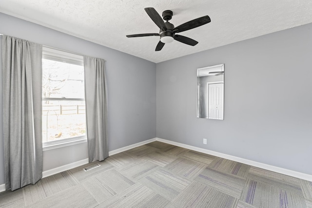 empty room with baseboards, visible vents, carpet floors, and a textured ceiling