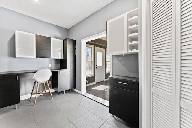 kitchen with dark countertops, a breakfast bar area, built in study area, and baseboards