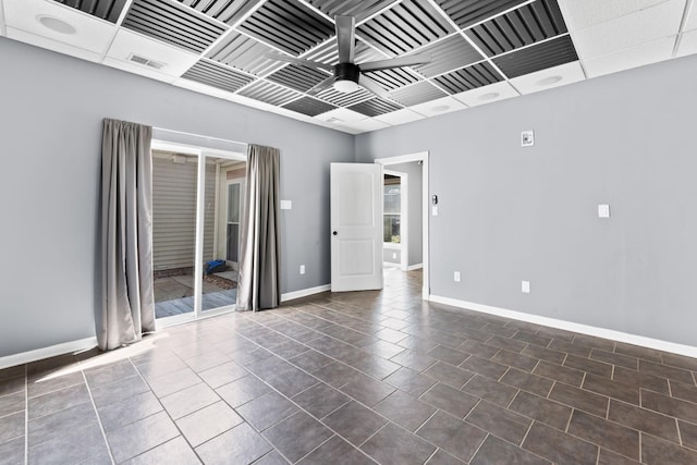 unfurnished room featuring dark tile patterned floors, baseboards, and ceiling fan