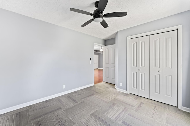 unfurnished bedroom featuring baseboards, carpet flooring, a closet, a textured ceiling, and a ceiling fan