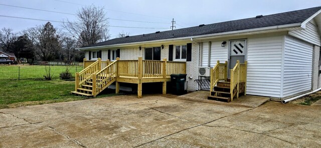 back of house with a wooden deck, brick siding, a lawn, and fence