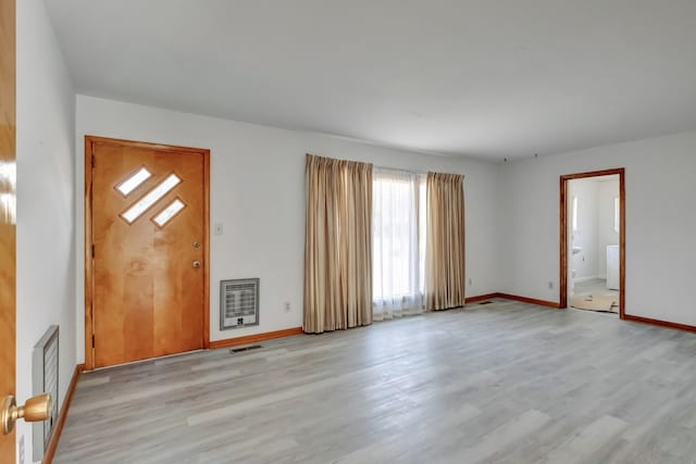 entrance foyer with heating unit, visible vents, baseboards, and wood finished floors