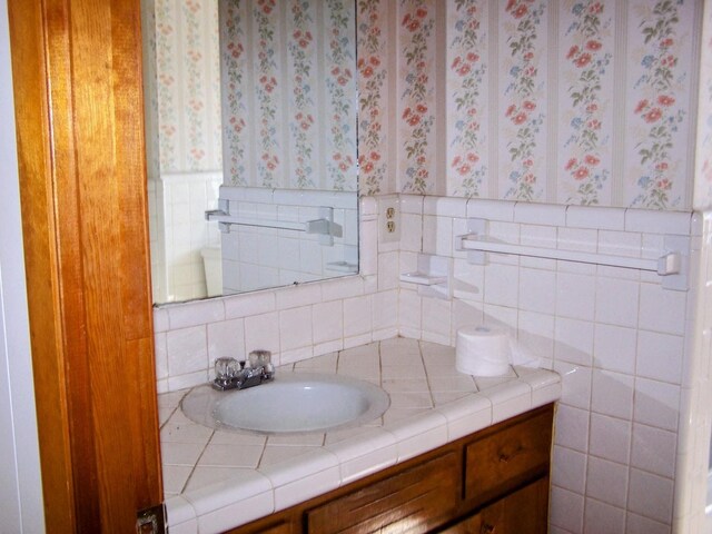 bathroom featuring wallpapered walls and vanity