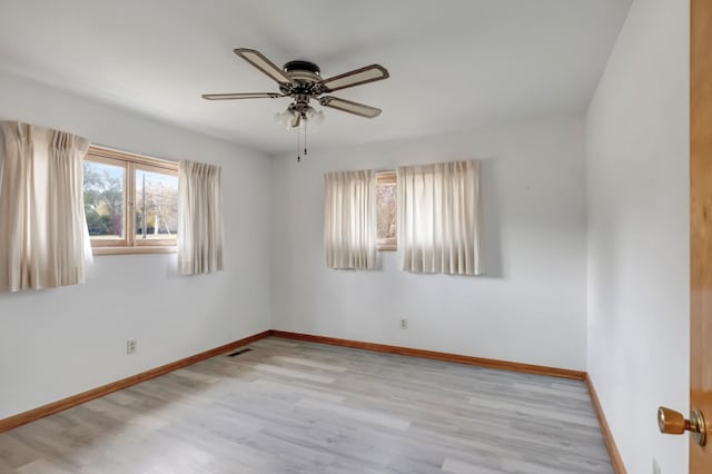 empty room featuring visible vents, a ceiling fan, baseboards, and wood finished floors