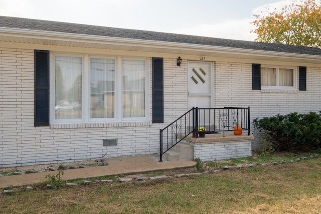 view of front of property featuring crawl space, brick siding, and roof with shingles