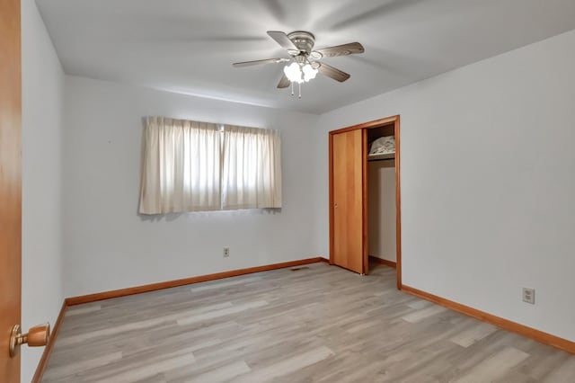 unfurnished bedroom featuring light wood-style floors, baseboards, a closet, and ceiling fan