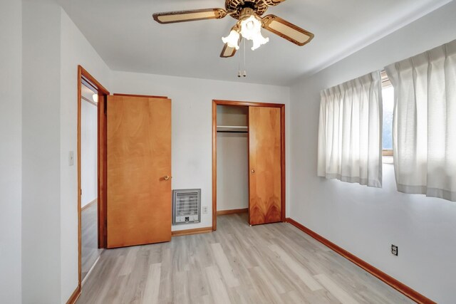 unfurnished bedroom with a ceiling fan, heating unit, wood finished floors, a closet, and baseboards