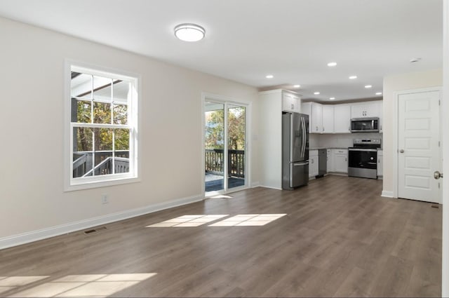 unfurnished living room with dark wood finished floors, visible vents, recessed lighting, and baseboards