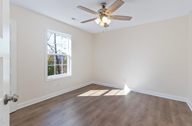 empty room with visible vents, wood finished floors, baseboards, and ceiling fan