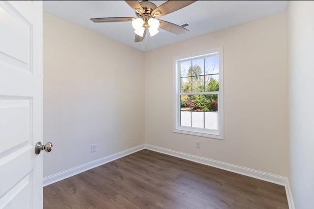 spare room with dark wood-style floors, visible vents, baseboards, and ceiling fan