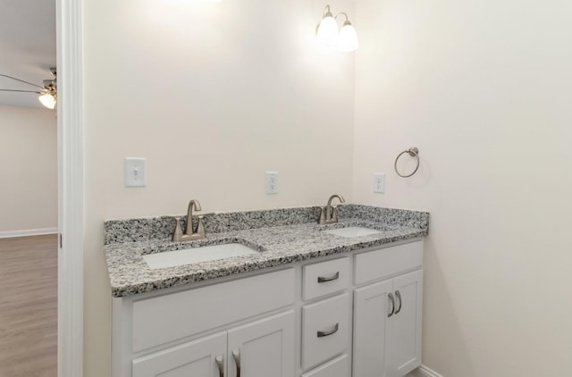 bathroom featuring a sink, baseboards, ceiling fan, and double vanity