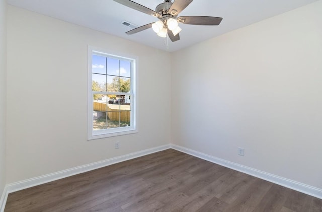 spare room with dark wood finished floors, visible vents, ceiling fan, and baseboards