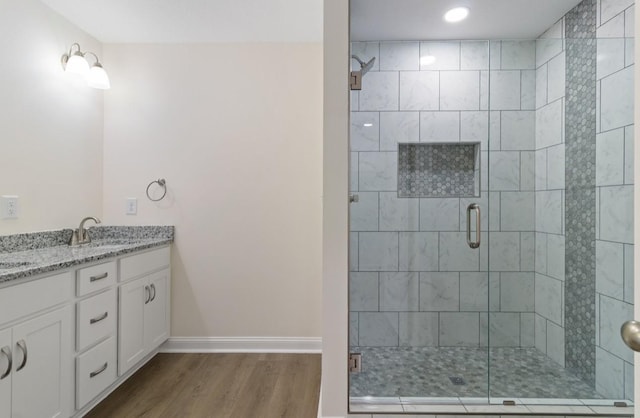 bathroom with vanity, a shower stall, wood finished floors, and baseboards