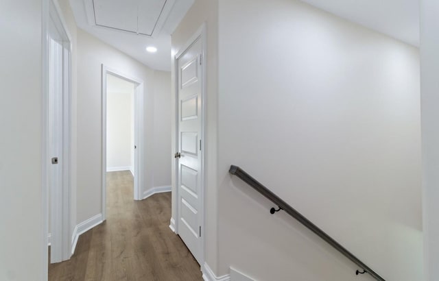 corridor featuring attic access, an upstairs landing, wood finished floors, and baseboards