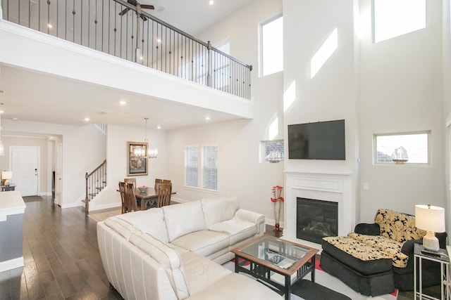 living area with dark wood finished floors, a glass covered fireplace, a healthy amount of sunlight, and baseboards