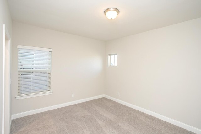 spare room featuring baseboards and light carpet