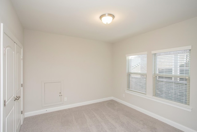 unfurnished room with light colored carpet and baseboards