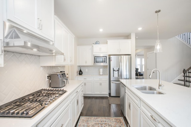 kitchen with under cabinet range hood, appliances with stainless steel finishes, white cabinets, and a sink