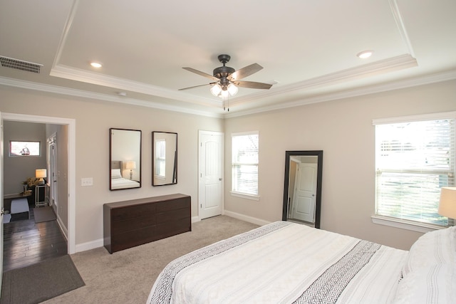 bedroom featuring visible vents, crown molding, baseboards, light colored carpet, and a raised ceiling