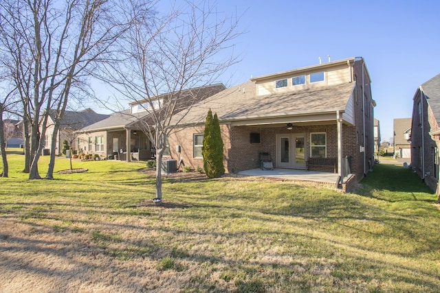 back of property with cooling unit, a yard, ceiling fan, a patio area, and brick siding