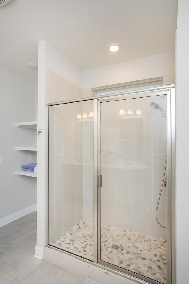 bathroom featuring tile patterned floors, baseboards, and a shower stall