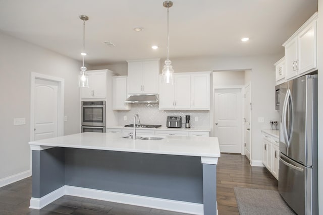 kitchen featuring tasteful backsplash, under cabinet range hood, light countertops, appliances with stainless steel finishes, and white cabinetry