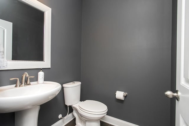 bathroom featuring toilet, baseboards, and a sink