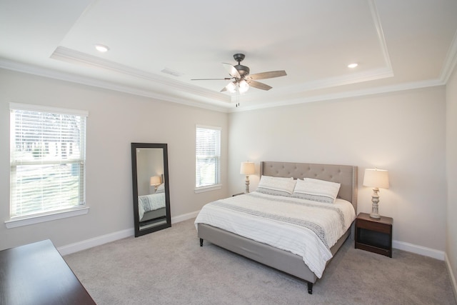 carpeted bedroom featuring visible vents, a ceiling fan, a tray ceiling, crown molding, and baseboards