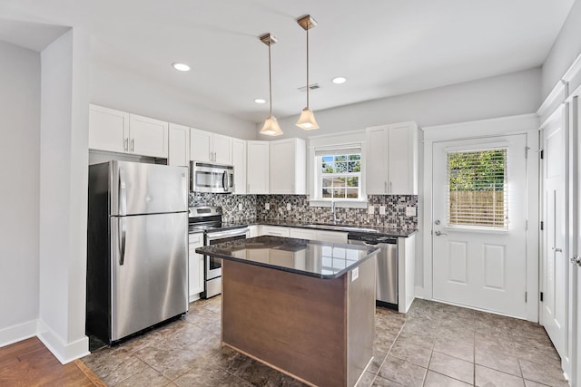 kitchen with visible vents, stainless steel appliances, decorative backsplash, white cabinets, and a center island