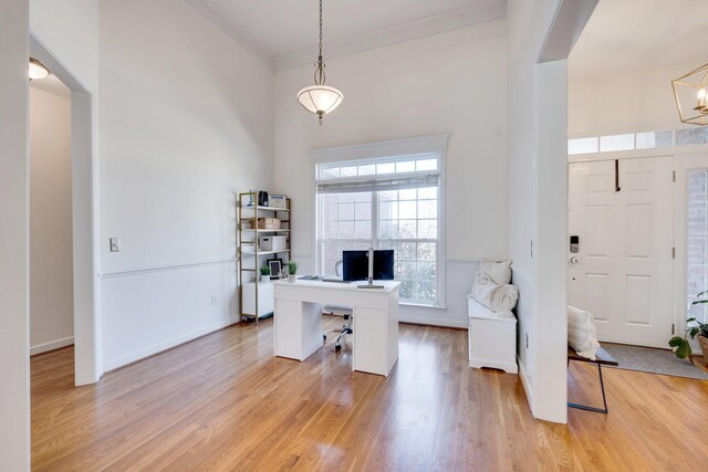 office space featuring a notable chandelier, baseboards, light wood finished floors, and ornamental molding