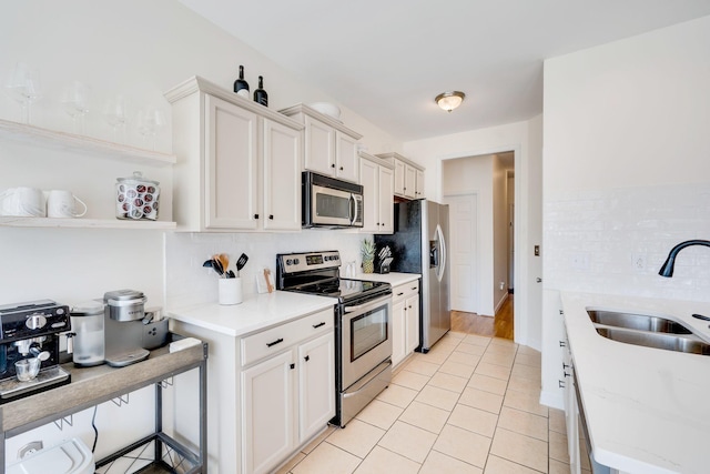 kitchen featuring backsplash, light countertops, light tile patterned floors, appliances with stainless steel finishes, and a sink