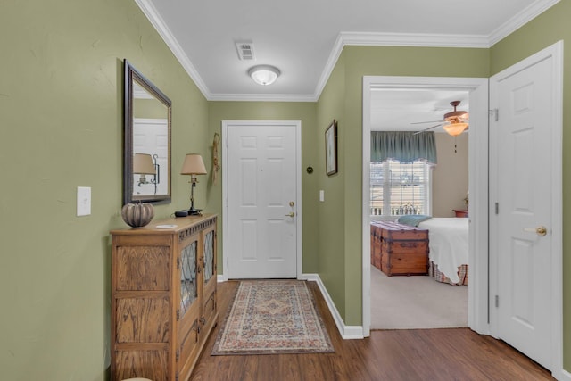 foyer with visible vents, baseboards, dark wood-type flooring, and crown molding