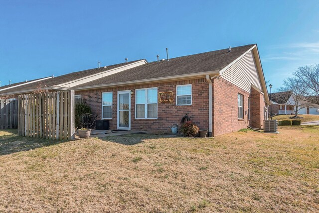 rear view of house with central air condition unit, a yard, fence, and brick siding