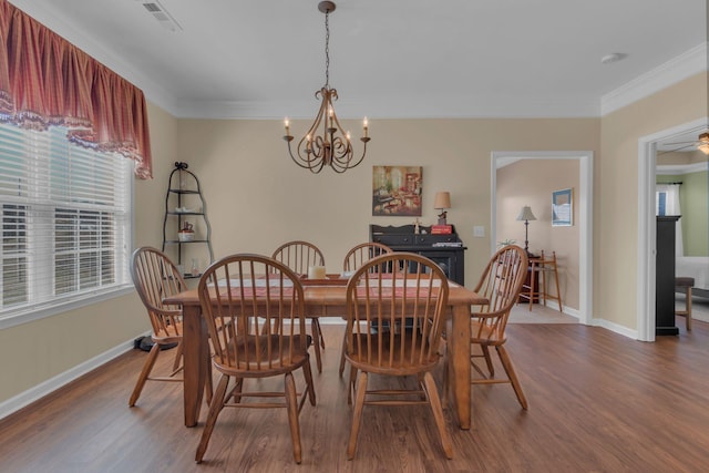 dining space with visible vents, baseboards, ornamental molding, wood finished floors, and a notable chandelier