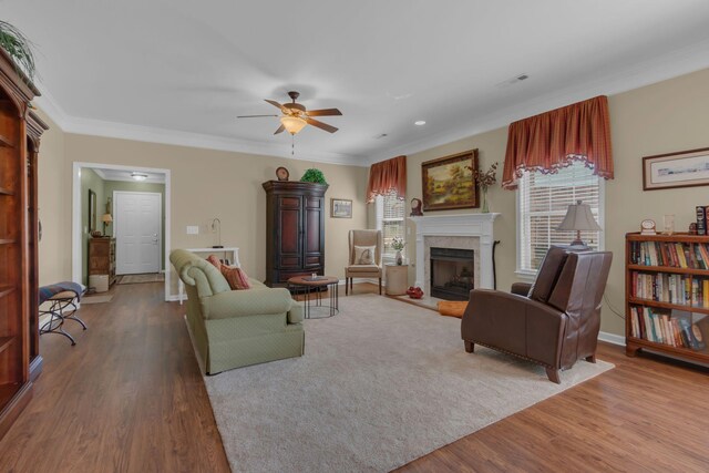 living area with a fireplace, crown molding, wood finished floors, and visible vents