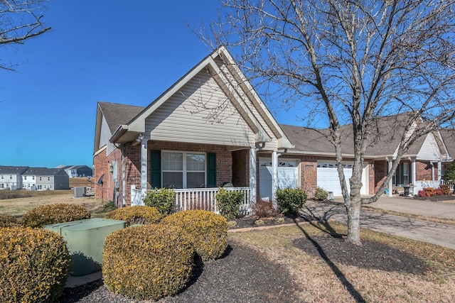 view of front of home featuring brick siding, an attached garage, a porch, and driveway