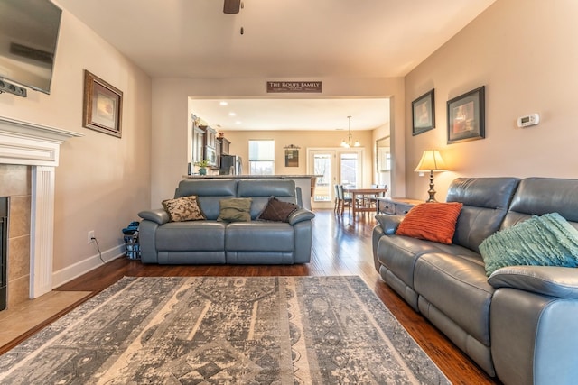 living area featuring a tiled fireplace, wood finished floors, and baseboards