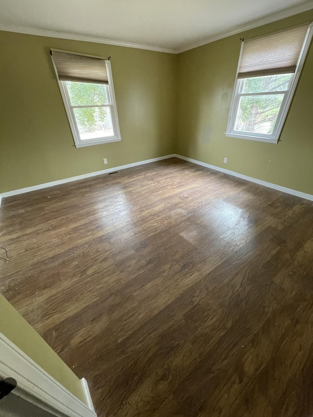 spare room featuring visible vents, baseboards, dark wood-style flooring, and crown molding