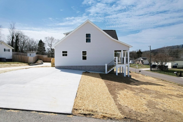 view of home's exterior with cooling unit, fence, and covered porch