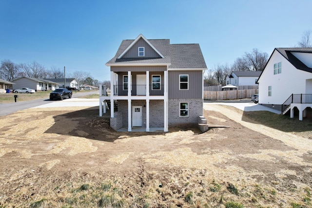 exterior space with a balcony, roof with shingles, and fence