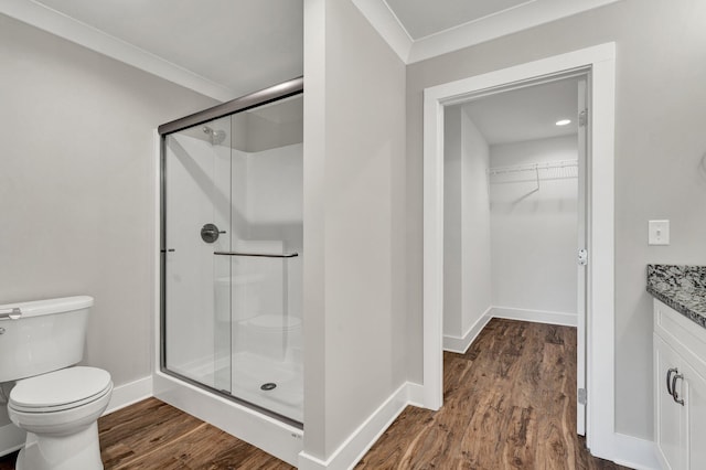 bathroom featuring a stall shower, toilet, vanity, and wood finished floors