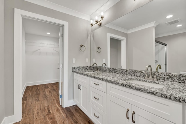 full bath with ornamental molding, wood finished floors, visible vents, and a sink