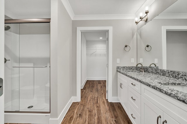 full bath with a shower stall, crown molding, wood finished floors, and a sink