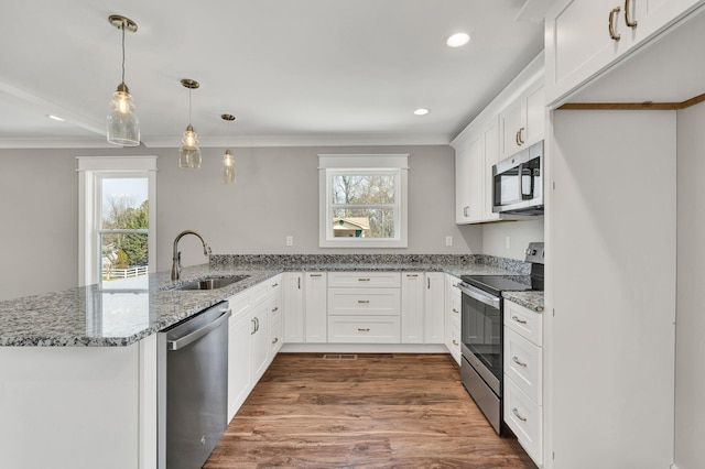 kitchen with plenty of natural light, a peninsula, stainless steel appliances, and a sink