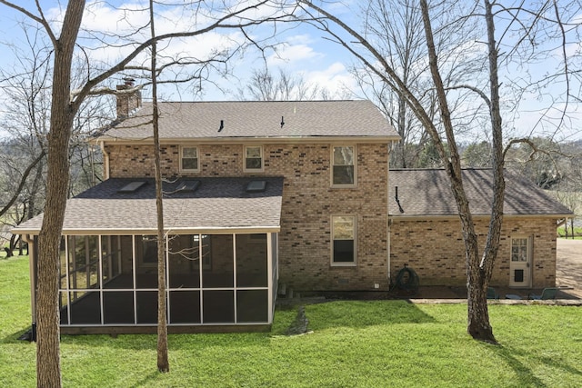 back of property featuring a sunroom, a shingled roof, a chimney, a lawn, and brick siding
